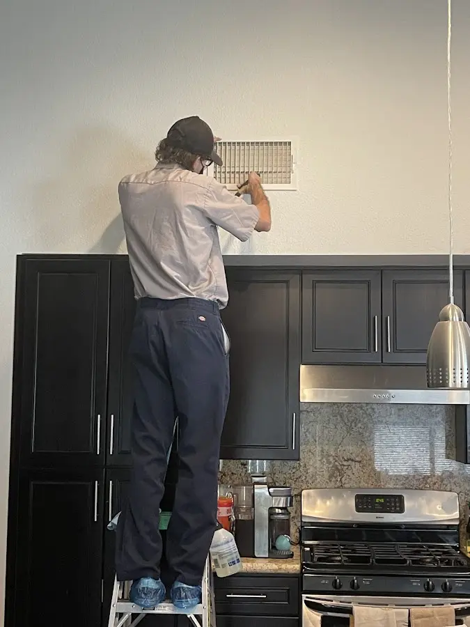 Technician inspecting an air vent during HVAC service in Grenada